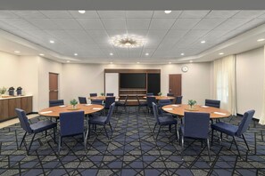 A conference room with round tables, chairs, a clock, and a ceiling light fixture. - Courtyard by Marriott Pittsburgh Monroeville (Monroeville)