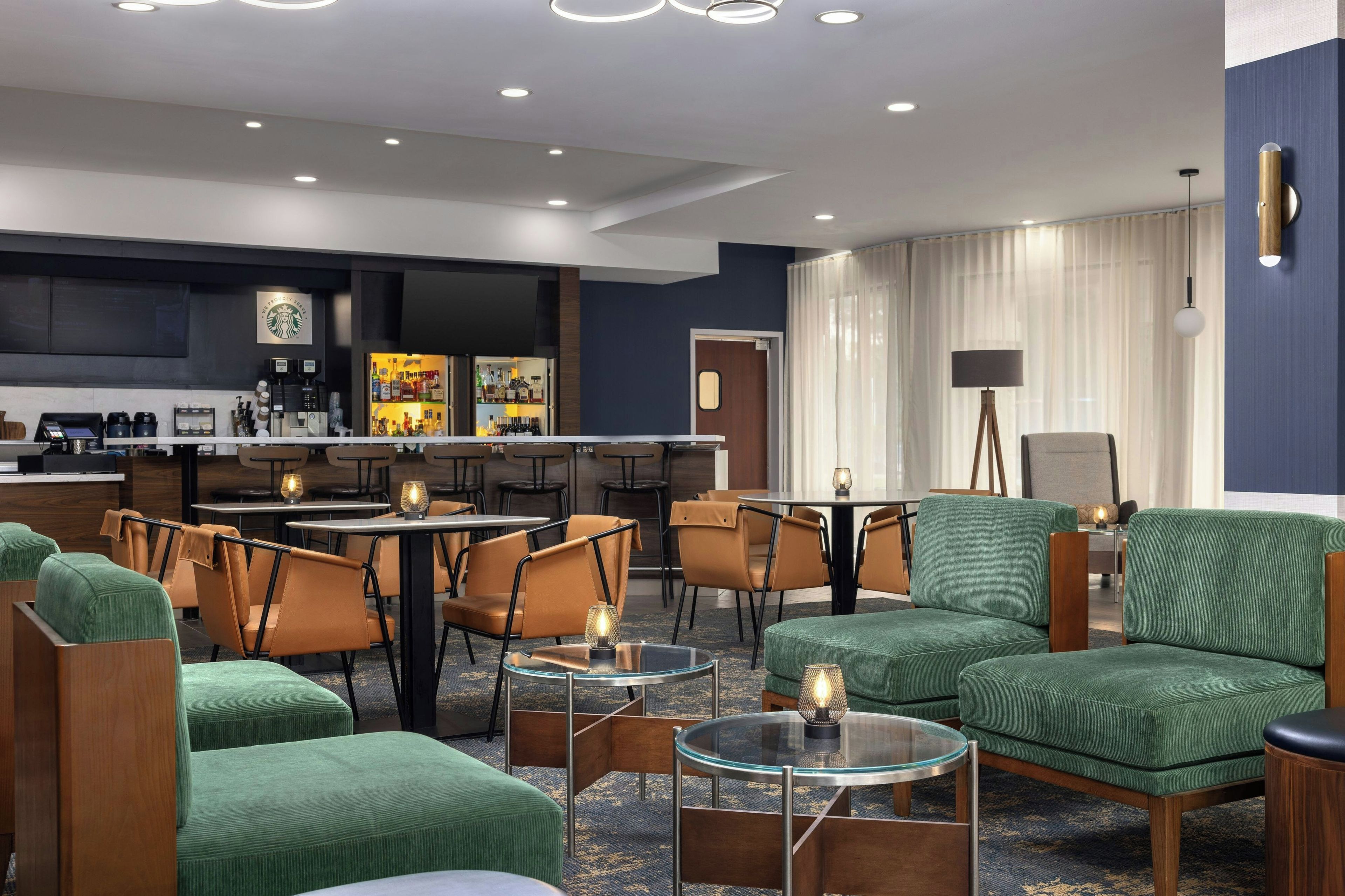 Um saguão de hotel com áreas de estar, um bar e uma mesa de recepção.