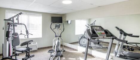 A fitness center with cardio machines, weight equipment, and a mirrored wall.