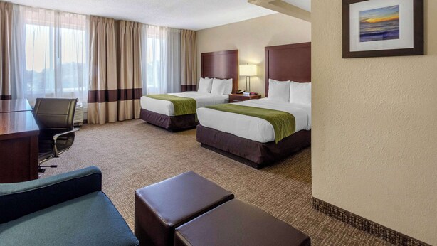 Une chambre d’hôtel avec deux lits, un bureau et une chaise.