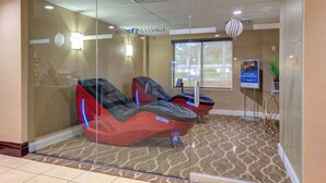 Un espace de massage à l’eau comprenant deux fauteuils de massage et une petite table agrémentée d’une plante.