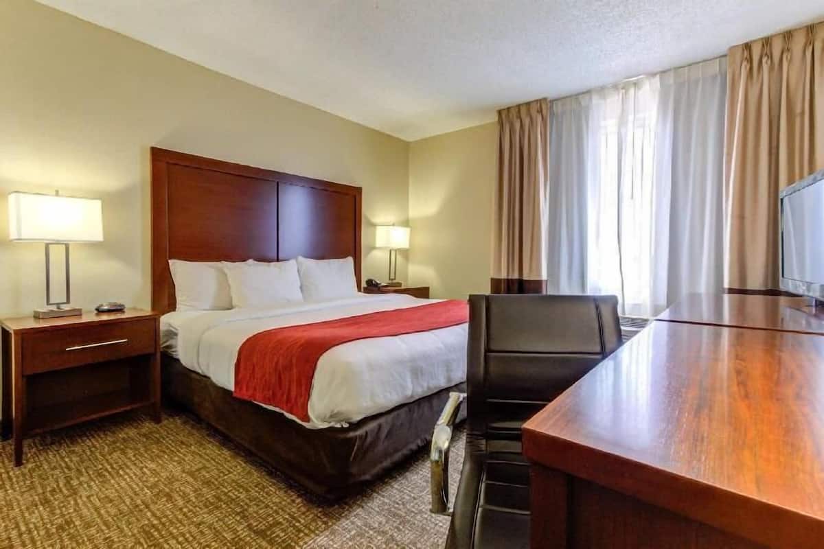 Una habitación de hotel con cama, lámparas de noche, escritorio y una silla.