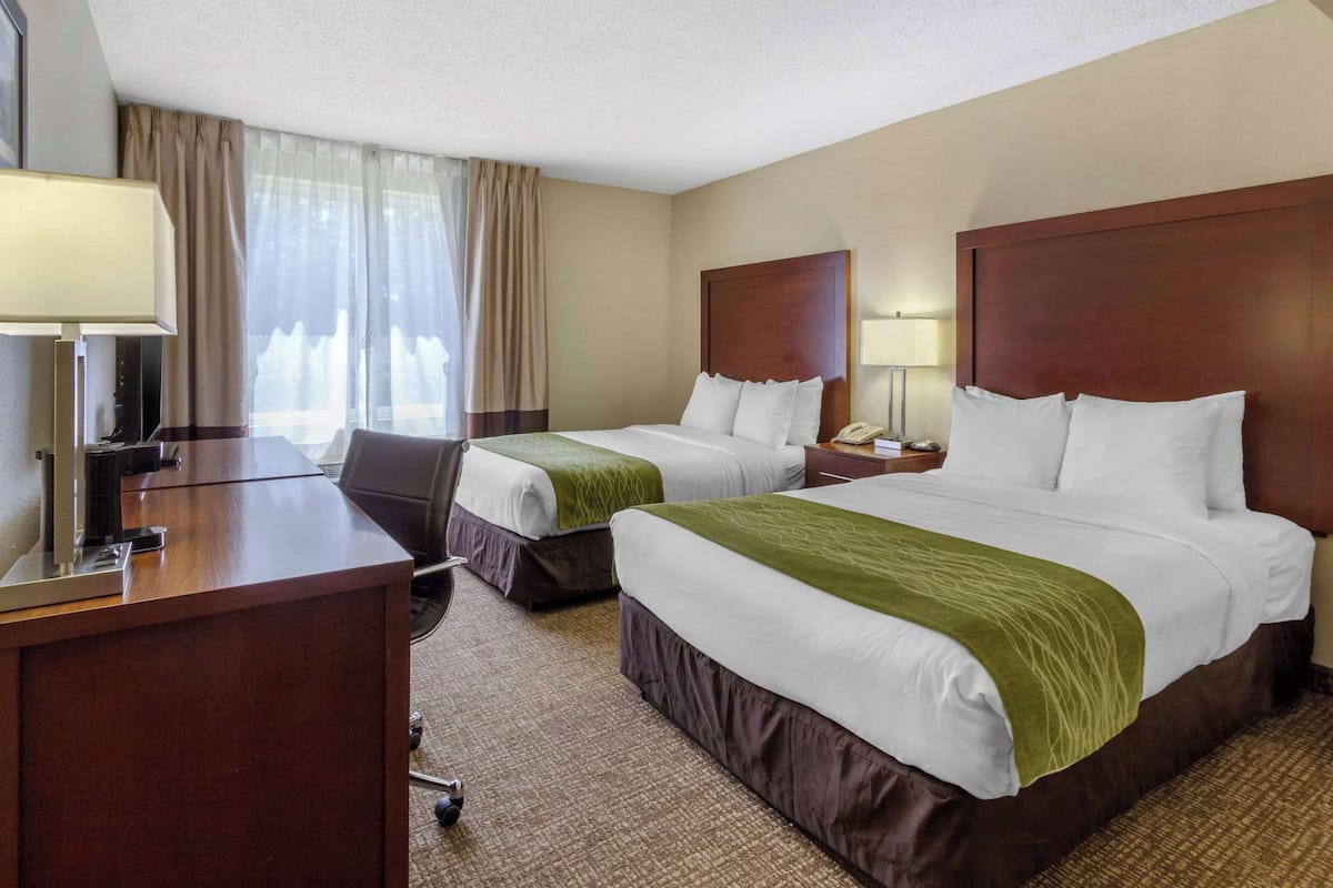 Habitación de hotel con dos camas, un escritorio y una silla.