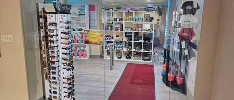 Una tienda con una variedad de gafas de sol y sombreros exhibidos en estantes y perchas.