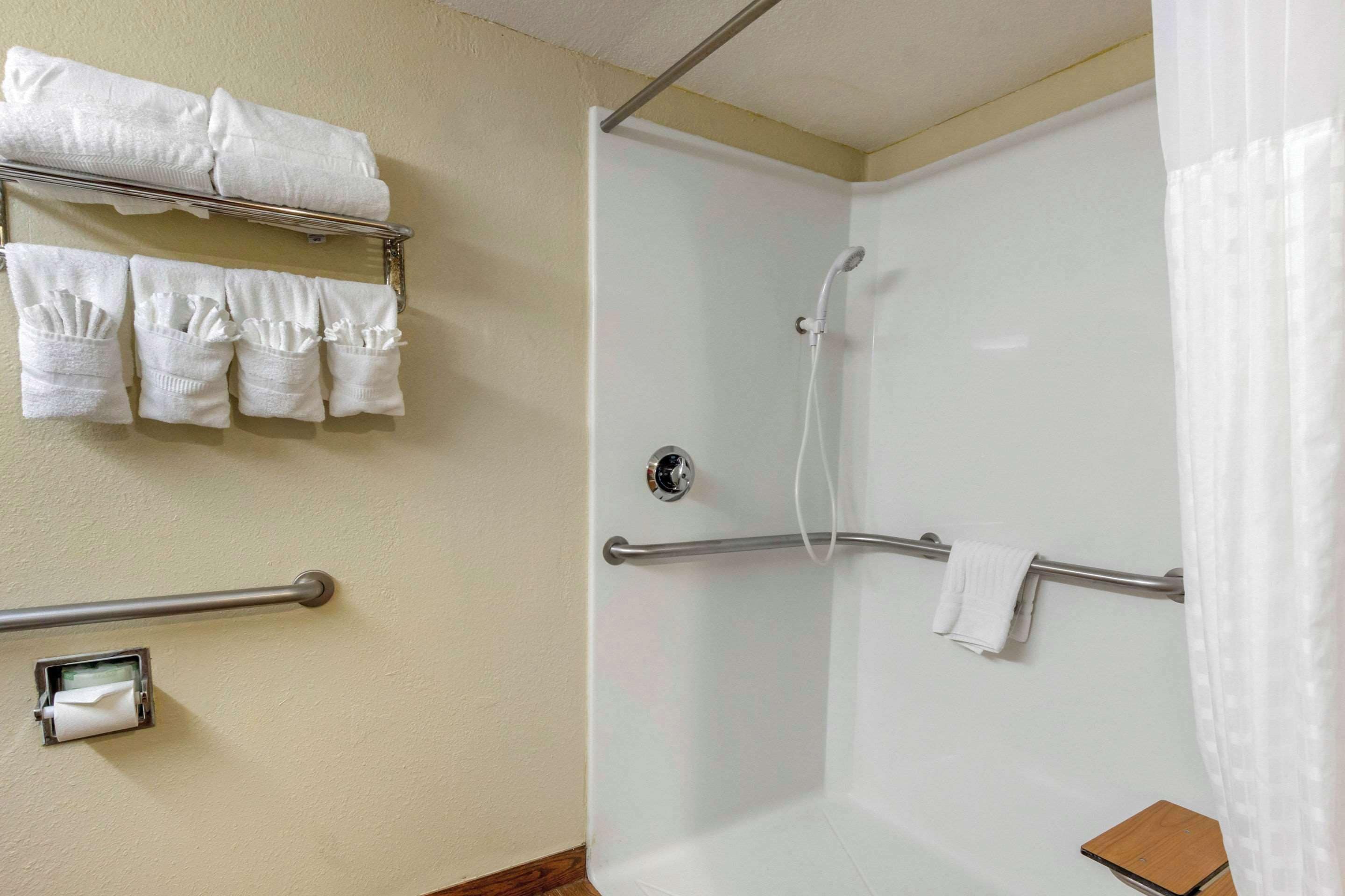 Casa de banho com chuveiro, toalheiro com várias toalhas e porta-papel higiénico.