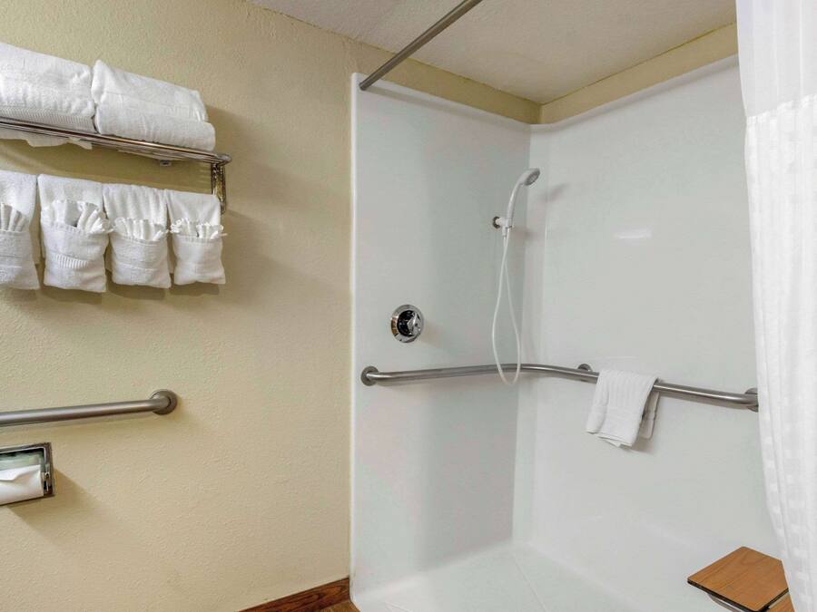 Casa de banho com chuveiro, toalheiro com várias toalhas e porta-papel higiénico.