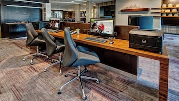 A modern office space with cubicles, a reception desk, and a printer.
