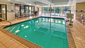 Un'area piscina con acqua cristallina, pavimento piastrellato e diverse poltrone prendisole.