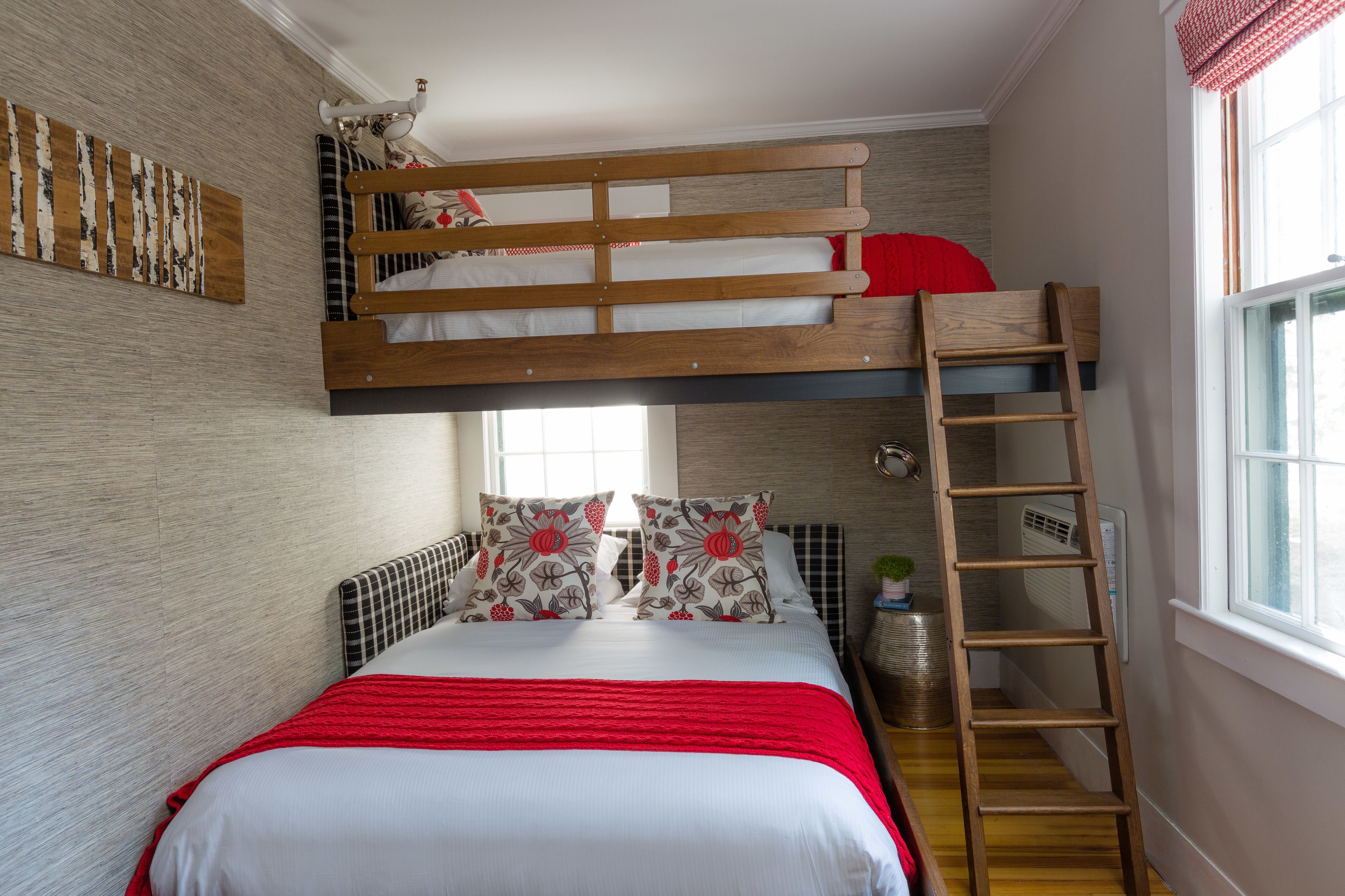 A bunk bed with a ladder, a red blanket, and a decorative pillow.