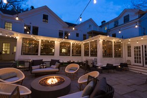 An outdoor patio with wicker furniture, a fire pit, and string lights.