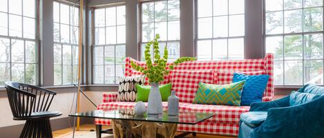 A living room with a red and white checkered sofa, a glass coffee table, and a blue armchair.