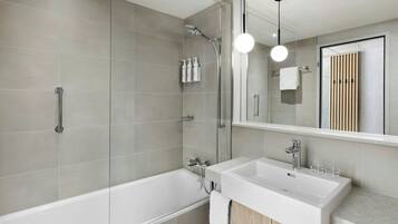 Ein modernes Badezimmer mit einer Badewanne, einer Dusche und einem Waschtisch mit Waschbecken und Spiegel.
