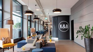 Un moderno vestíbulo de hotel con áreas de estar, ventanas grandes y un letrero llamativo de K&B.