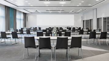Un salón de conferencias con una gran mesa, sillas negras y botellas de agua.