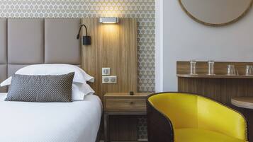 A hotel room with a bed, bedside table, lamp, and a yellow chair.