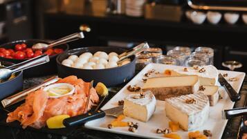 A buffet with various cheeses, smoked salmon, and fruits.