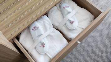Cajón de madera con toallas blancas dobladas ordenadamente y pantuflas con un logotipo.