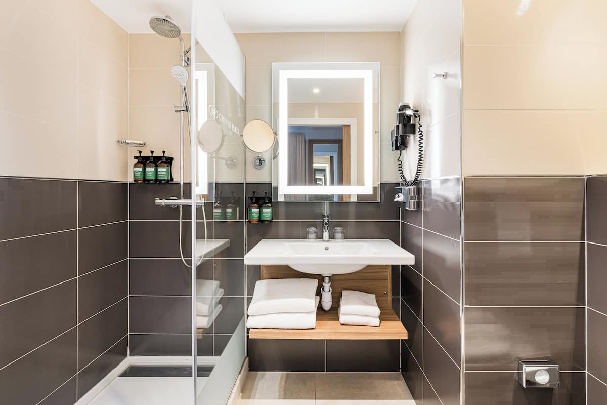 A modern bathroom with a large mirror, a shower, and a sink.
