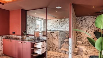 Une salle de bain moderne avec des murs en marbre, un meuble-lavabo rose et un grand miroir.