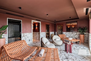 Un área de spa con sillones de mimbre, suelo de mármol y una planta grande en maceta.