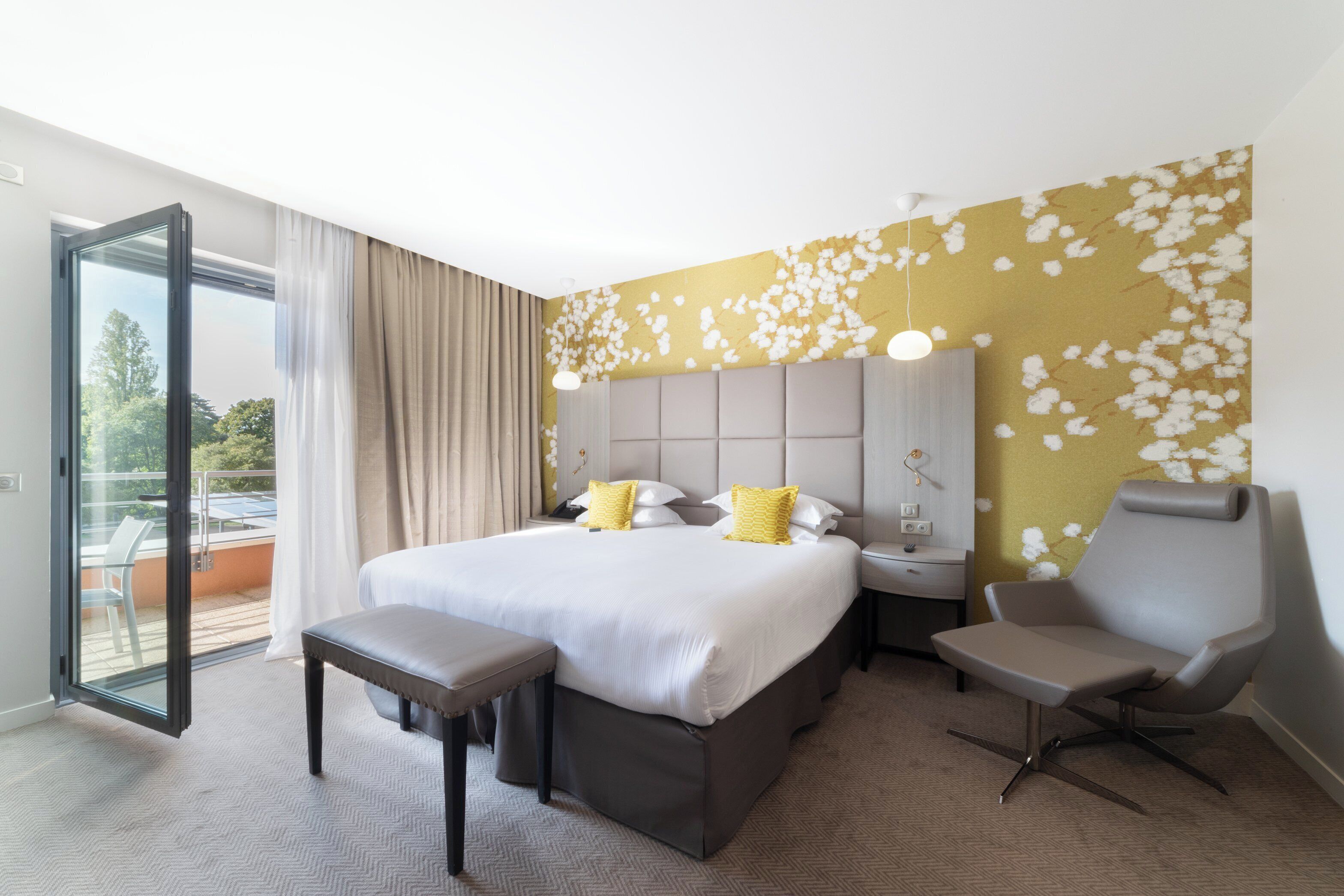 Una habitación de hotel moderna con una cama grande, una zona de estar y un balcón.