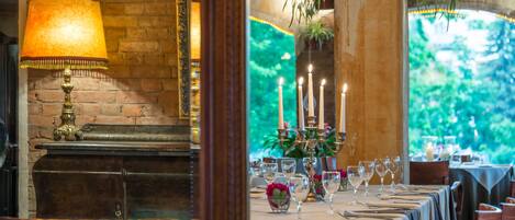 A restaurant with a brick wall, a brass lamp, and a table set with wine glasses and candles.