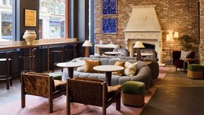 A cozy lounge area with a brick wall, a fireplace, and comfortable seating. - The Hoxton, Shoreditch (London)