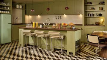 A kitchen with a checkered floor, green cabinets, and a bar area with stools.