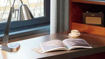 En modern arbetsplats med ett skrivbord, en stol, en lampa, en öppen bok och en kopp kaffe.