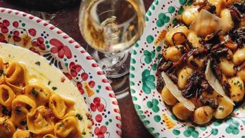 A table with plates of food, including pasta and breaded items, and a glass of wine.