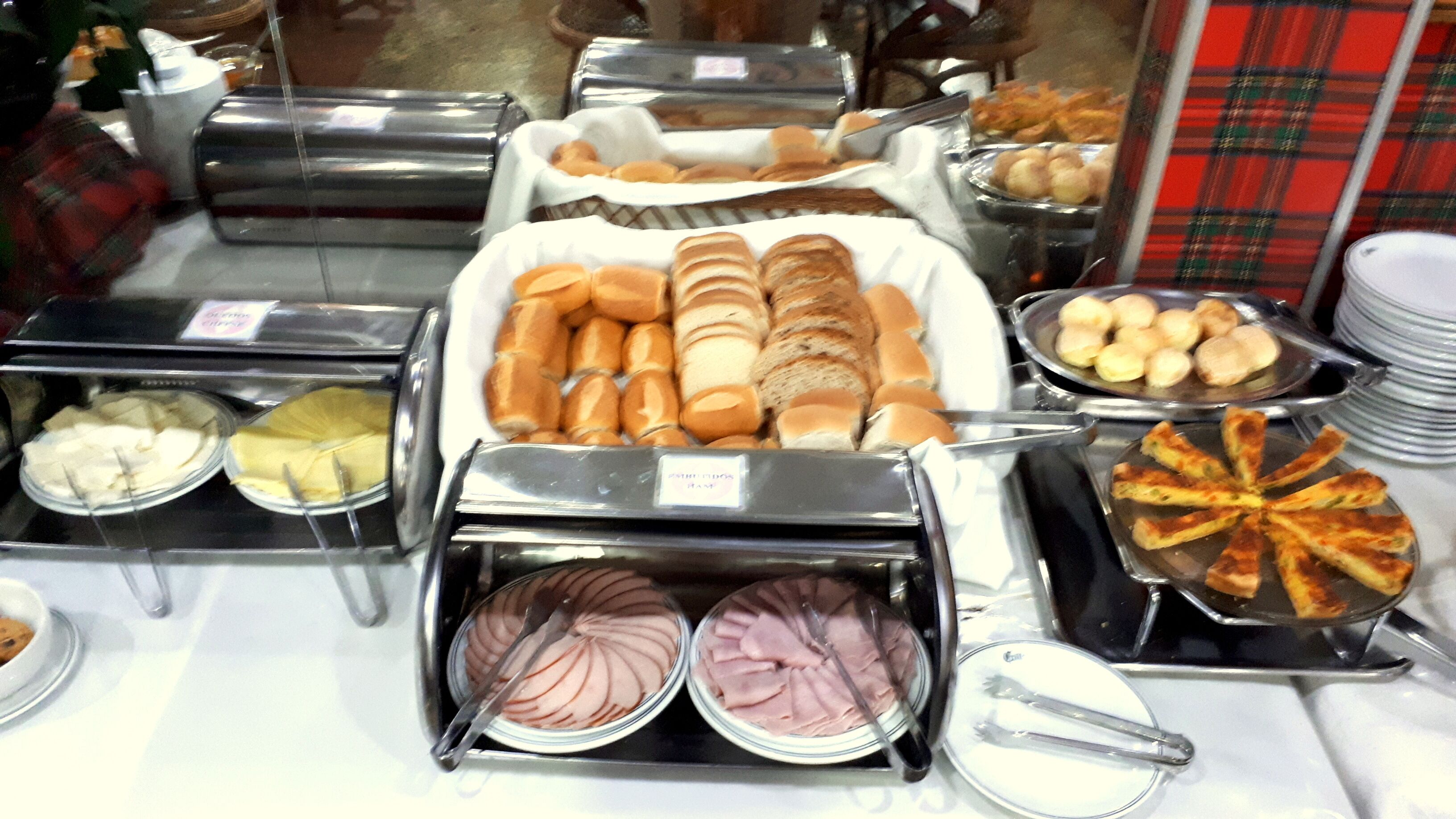 Buffet com diversos alimentos, incluindo pão, doces e fatias de carne.