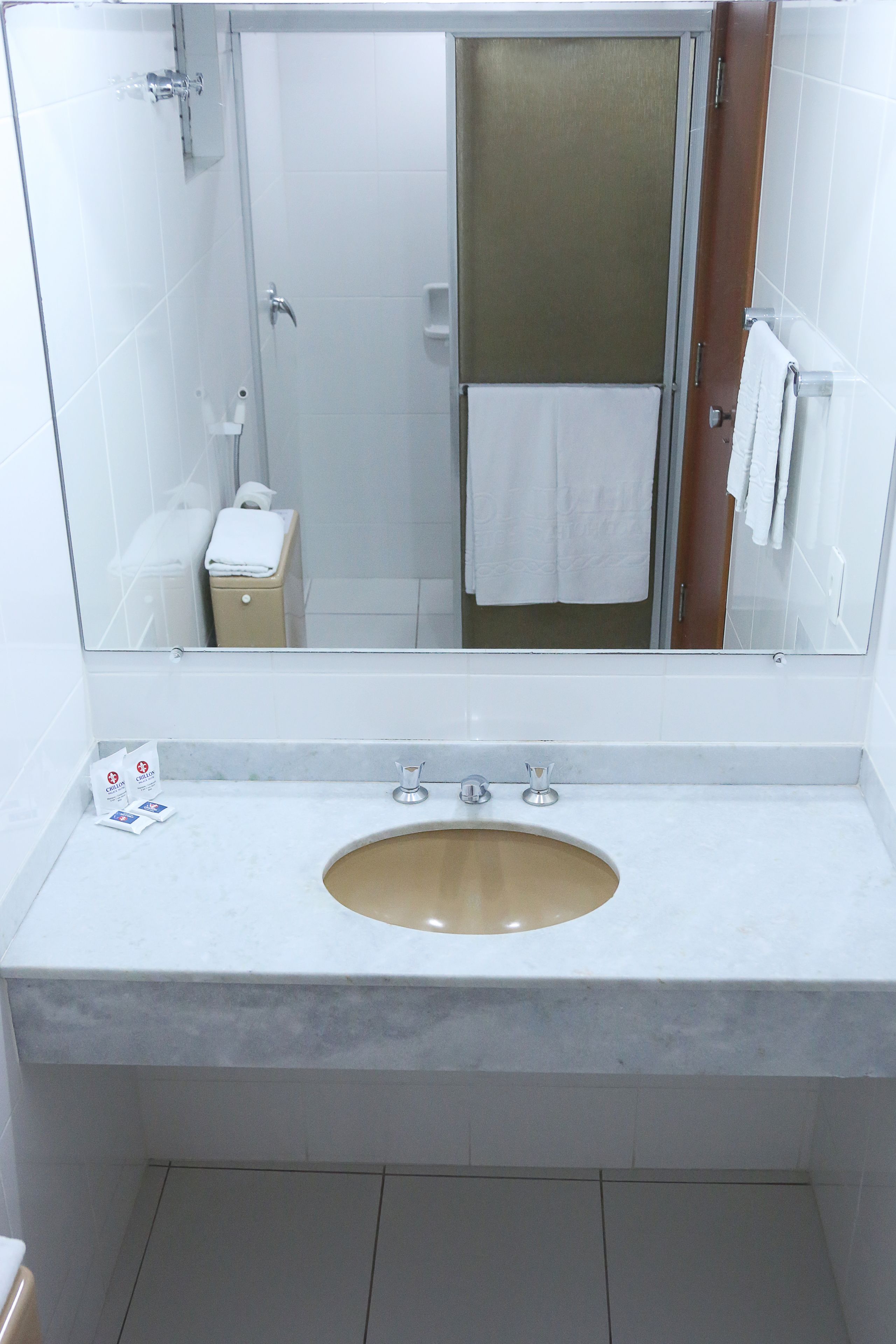 A bathroom with a large mirror, a sink, a shower, and a toilet.