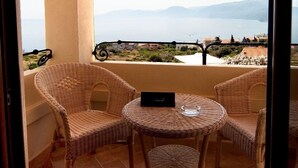 A balcony with wicker chairs and a small table, overlooking a scenic view of mountains and a body of water. - Hotel Villa Gustui Maris (Dorgali)