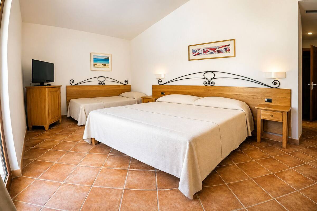 A hotel room with a large bed, two bedside tables, a TV, and artwork on the walls.
