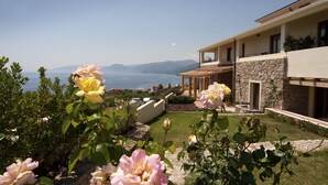 A modern house with a stone facade, a balcony, and a view of the sea. - Hotel Villa Gustui Maris (Dorgali)
