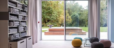 Ein modernes Interieur mit einem großen Schiebeglasfenster, das zu einem Gartenbereich im Freien führt.