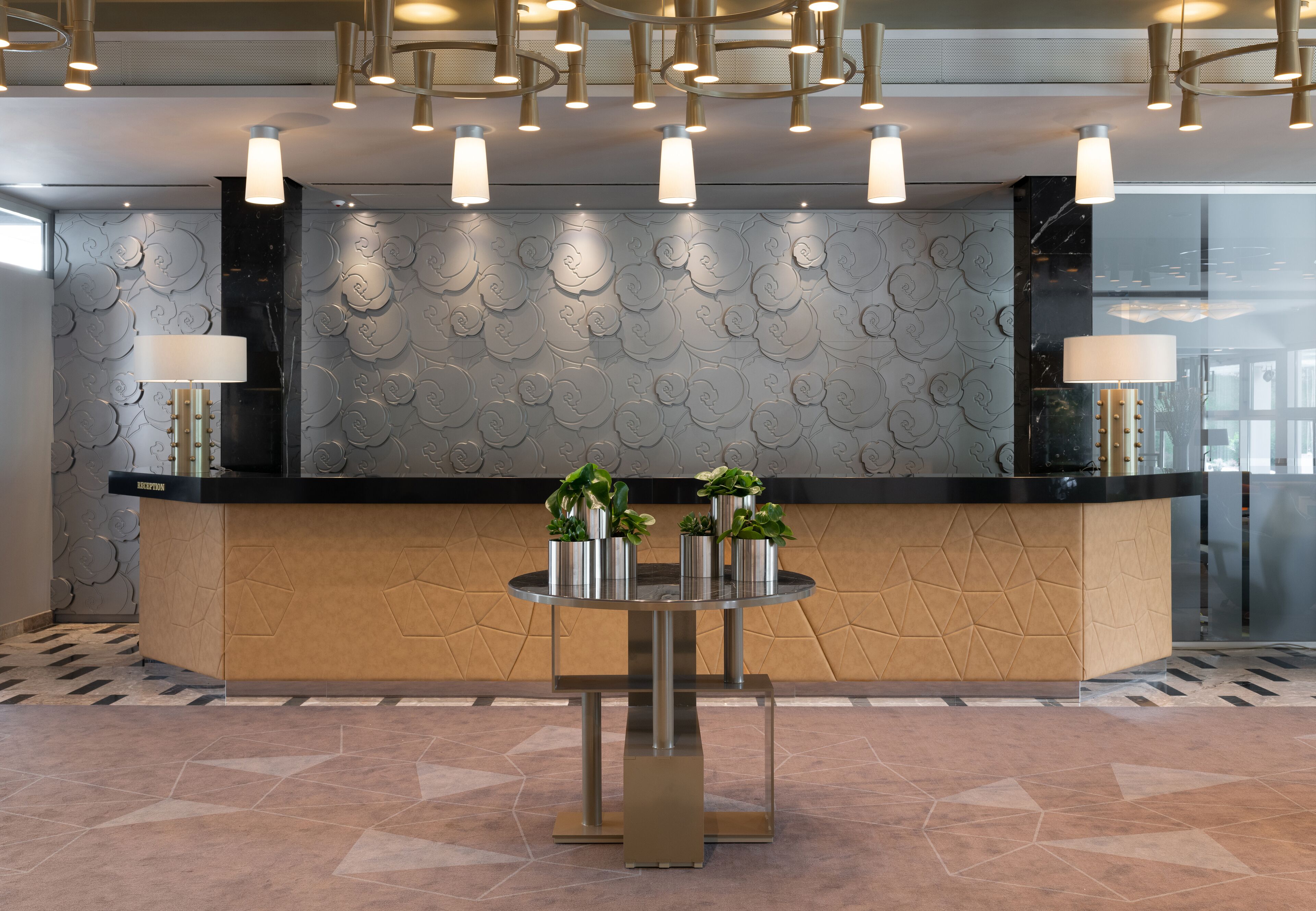A reception desk with a modern design, featuring a round table in front and a patterned wall behind.