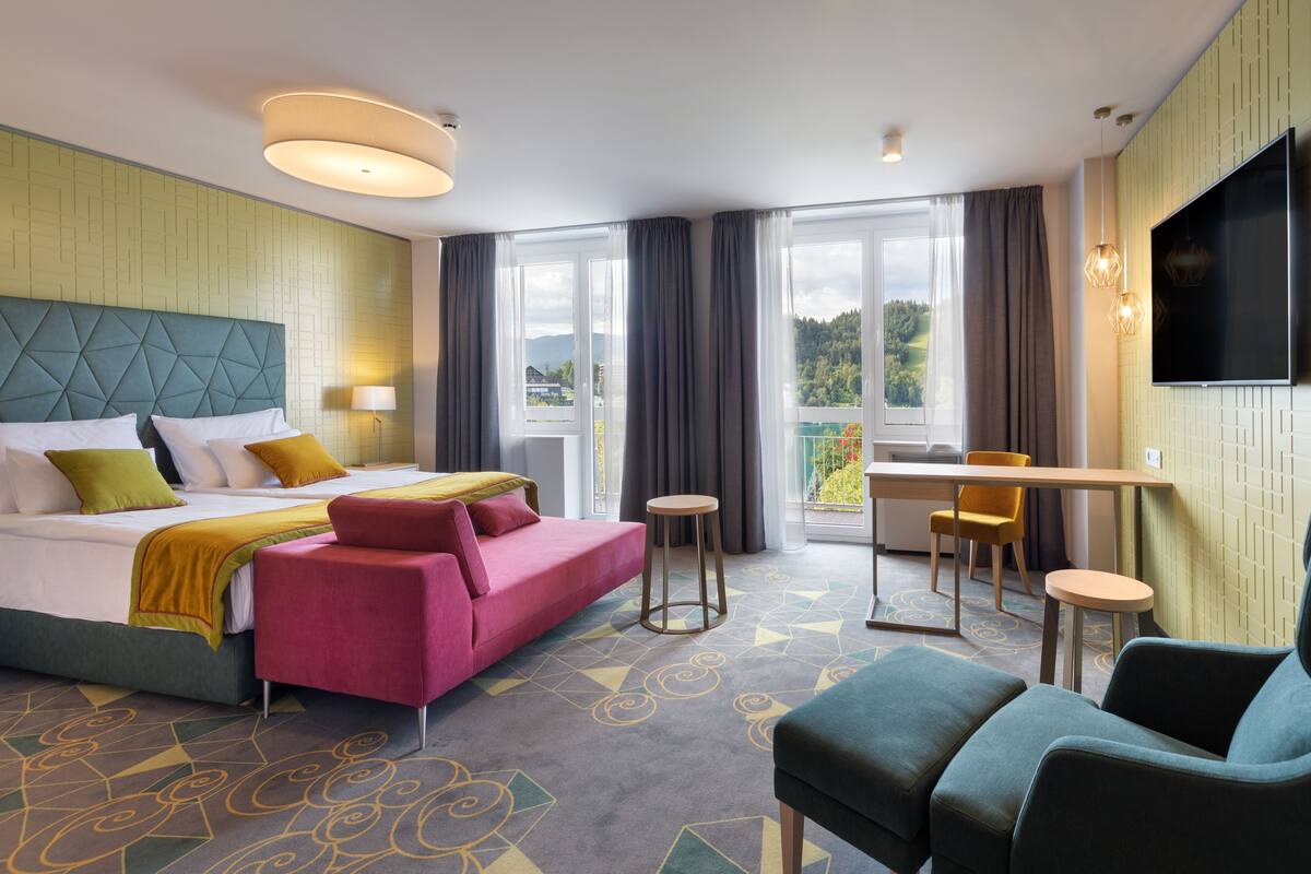 A hotel room with a bed, a desk, a sofa, and a TV.