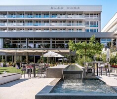 Un hotel moderno con terraza en la azotea, mobiliario exterior y una fuente.