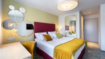 Une chambre d’hôtel avec un grand lit, une table de chevet, un miroir et un luminaire au plafond.