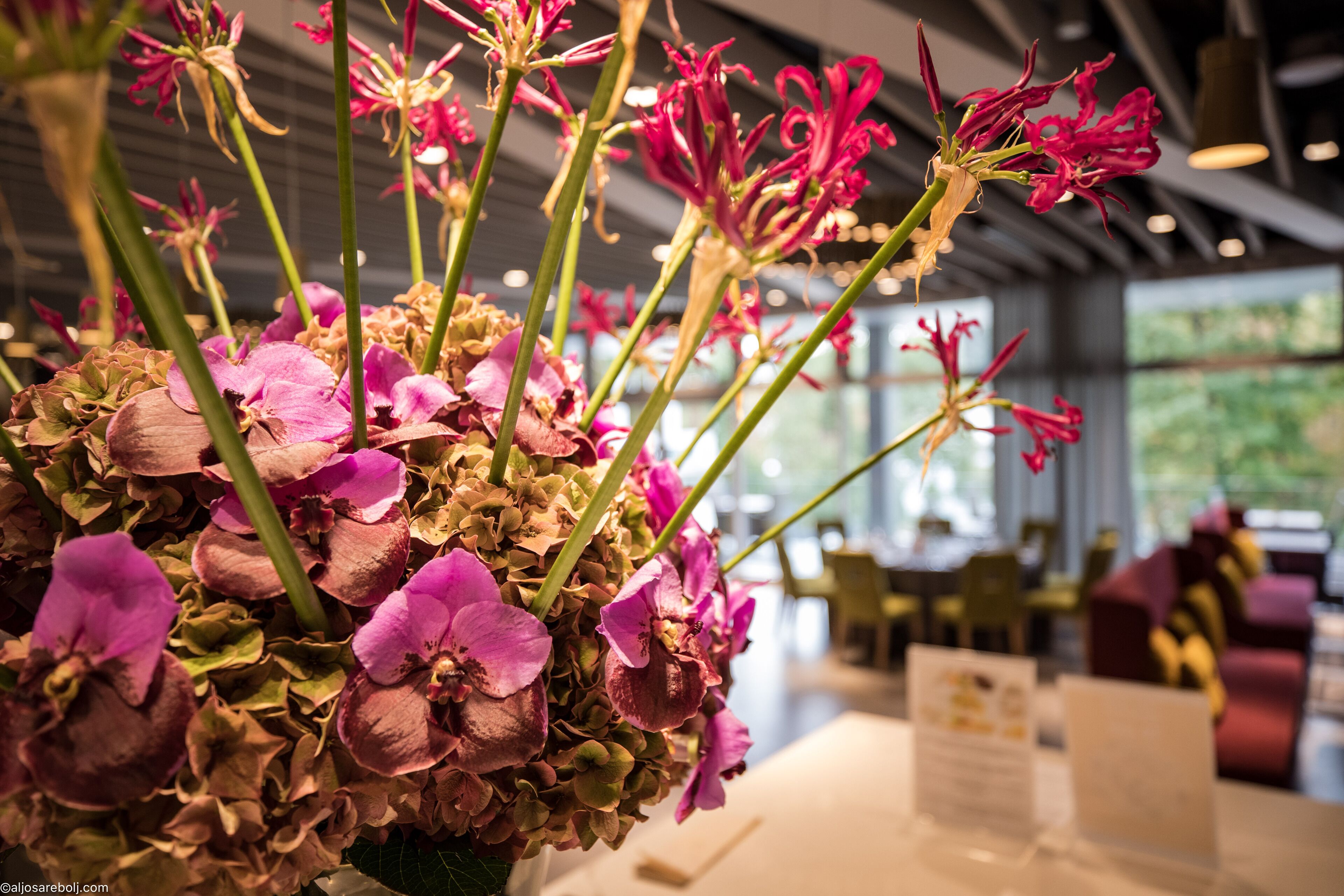 A floral arrangement in a modern interior space with visible seating and tables.