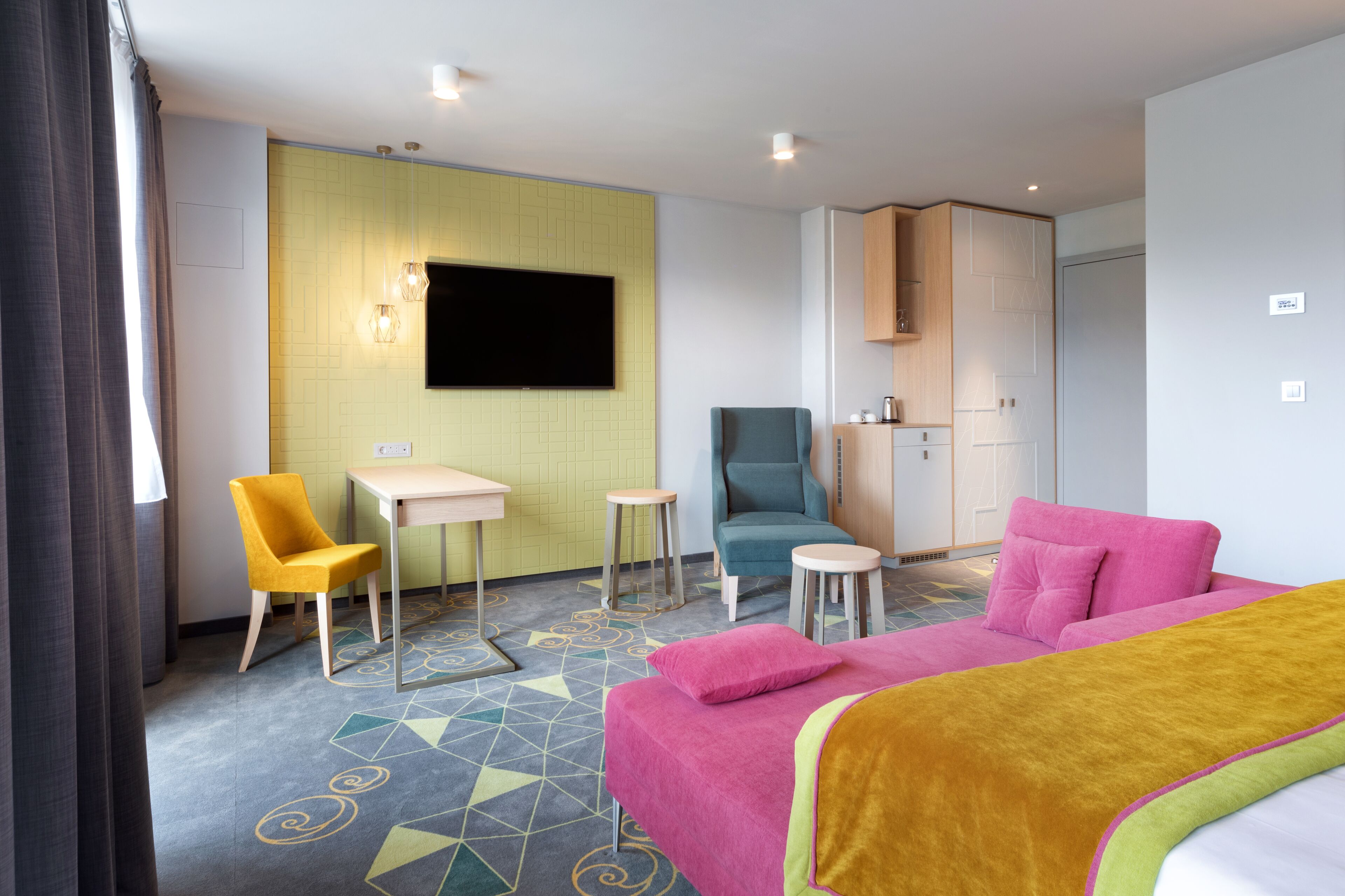 A hotel room with a bed, a desk, a chair, and a television.
