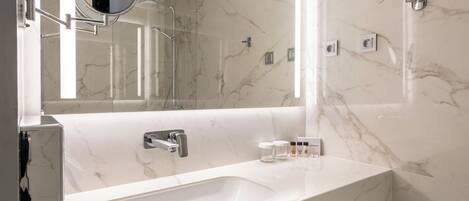 A modern bathroom with a marble sink, a mirror, and a shower.