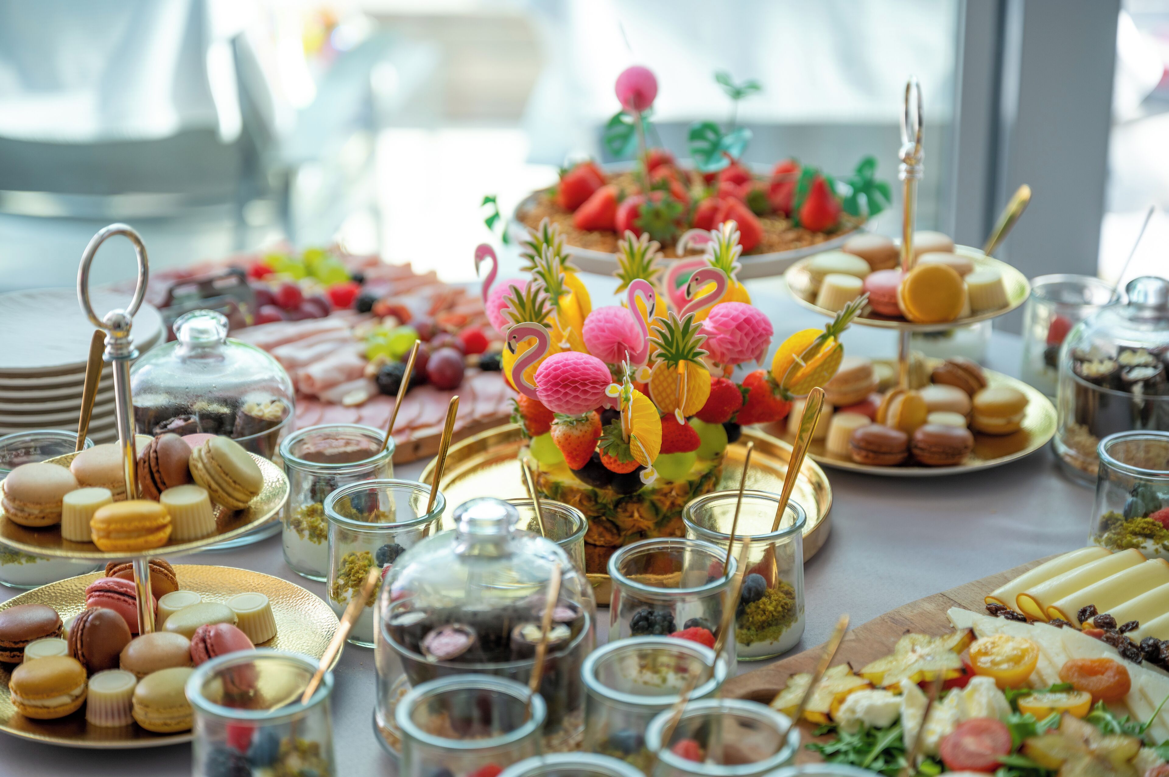 A buffet table with various food items including macarons, fruits, and desserts.