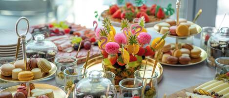 A buffet table with various food items including macarons, fruits, and desserts.