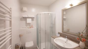 Un bagno moderno con box doccia in vetro, un lavandino bianco e uno specchio grande.