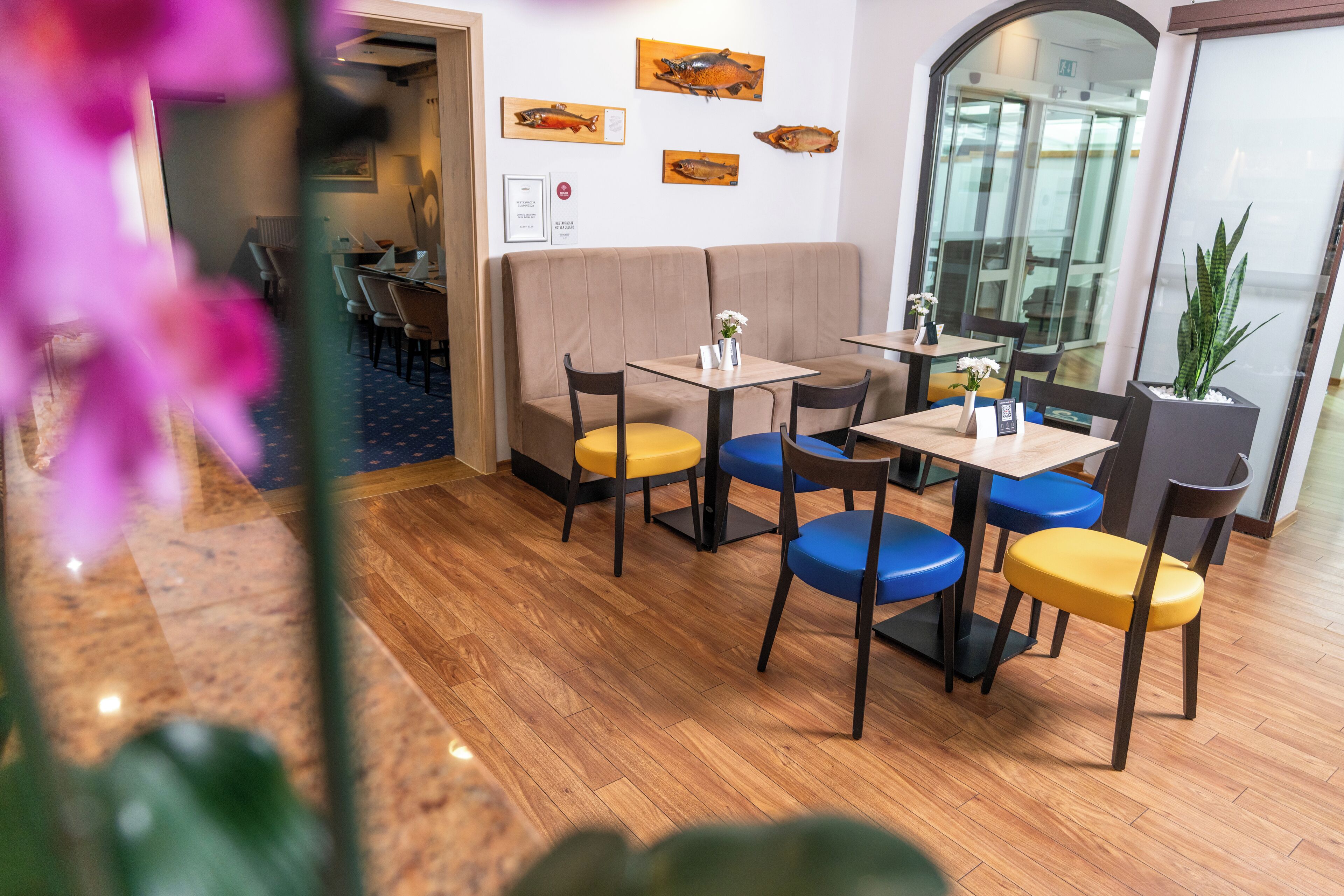 A restaurant with wooden flooring, booths, and colorful chairs.