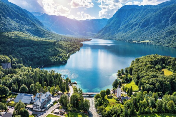 Eine gebirgige Landschaft mit einem See, einer Brücke und Gebäuden im modernen Baustil.