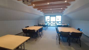 A conference room with a high ceiling, wooden beams, and large windows.
