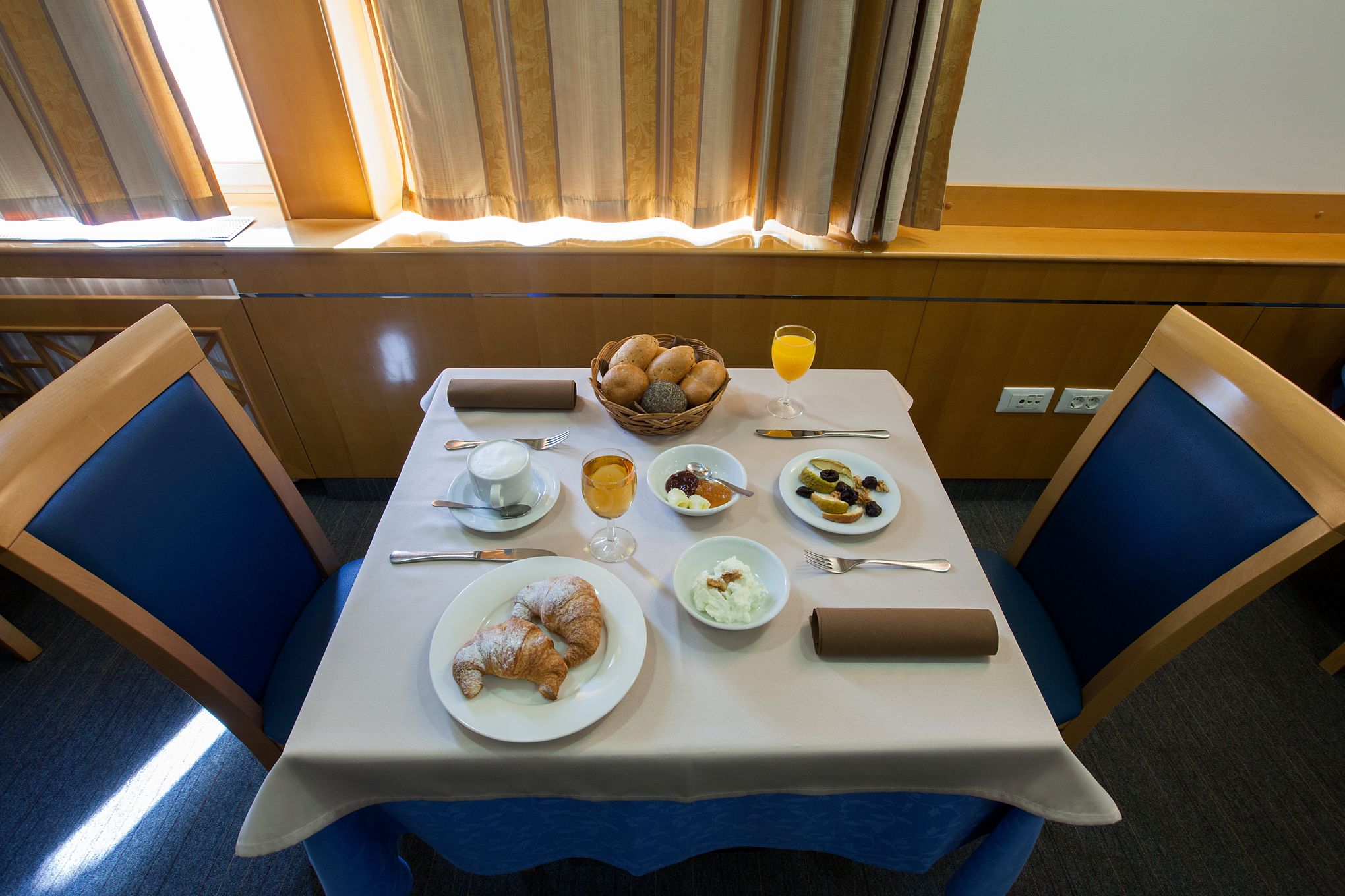 Una tavola imbandita per la colazione con croissant, frutta e un bicchiere di succo d'arancia.